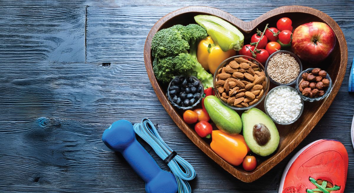 Heart shaped plate full of healthy foods with training equipment and running shoe